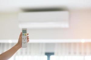hand using remote controller for adjust Air conditioner inside the room of office or home photo