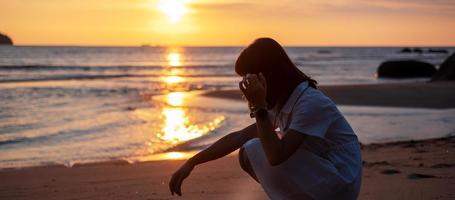 Silhouette of young woman against beautiful sunset at the beach. Travel, relaxing, vacation summer concept photo