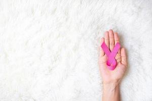 October Breast Cancer Awareness month, adult Woman  hand holding Pink Ribbon on pink background for supporting people living and illness. International Women, Mother and World cancer day concept photo