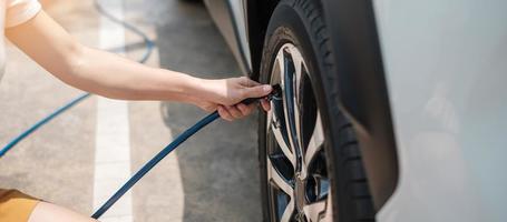 inflando a mano los neumáticos del vehículo, comprobando la presión del aire y llenando el aire en la rueda del coche en la gasolinera. concepto de transporte de autoservicio, mantenimiento y seguridad foto