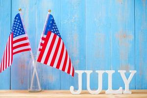texto de julio y bandera de los estados unidos de américa sobre fondo de mesa de madera. EE.UU. fiesta de la independencia y los conceptos de celebración foto