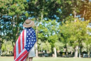 mujer que viaja con la bandera de los Estados Unidos de América en el parque al aire libre. fiesta de los veteranos en estados unidos, memorial, independencia y concepto del día del trabajo foto