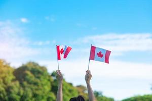 hand holding Canada flag on blue sky background. Canada Day  and happy celebration concepts photo