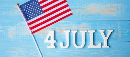 Fourth of July text and United States of America flag on wooden table background. USA holiday of Independence and celebration concepts photo