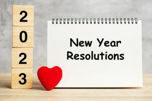 palabras de resolución de año nuevo y cubos de 2023 con decoración en forma de corazón rojo en la mesa. concepto de objetivo, plan, salud, amor y feliz día de San Valentín foto
