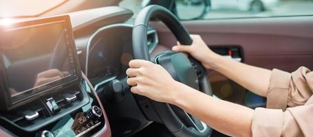 woman driver driving a car on the road, hand controlling steering wheel in electric modern automobile. Journey, trip and safety Transportation concepts photo