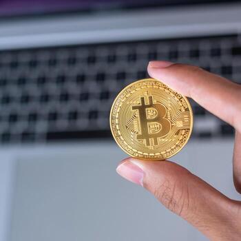 Businessman hand holding golden Bitcoin cryptocurrency over laptop keyboard, Crypto is Digital Money within the blockchain network, is exchanged using technology and online exchange concept photo