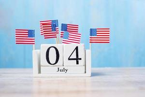 Wooden calendar of July 4th with miniature United States of America flag on wood background. Independence day and nation Holiday concept photo