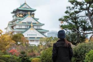 solo woman tourist trveling at Osaka castle in Autumn season, Asian traveler visit in Osaka city, Japan. Vacation, destination and travel concept photo