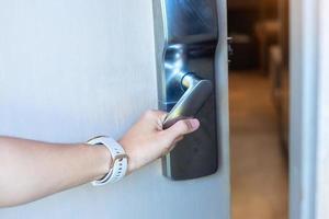 mujer sosteniendo el mango de la cerradura digital inteligente entre abrir o cerrar la puerta. conceptos de tecnología, electricidad y estilo de vida foto