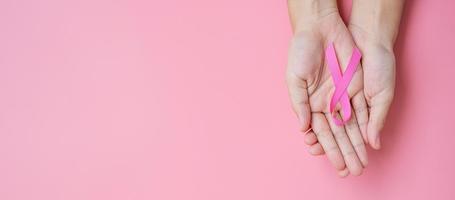 October Breast Cancer Awareness month, adult Woman hand holding Pink Ribbon on pink background for supporting people living and illness. International Women, Mother and World cancer day concept photo