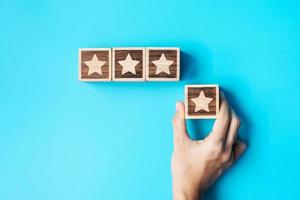 hand holding Star block on blue background. Customer choose rating for user reviews. Service rating, ranking, customer review, satisfaction, evaluation and feedback concept photo