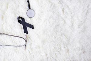 black Ribbon and stethoscope on white background. Melanoma and skin cancer, Vaccine injury awareness month and rest in peace concepts photo