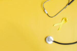 Yellow Ribbon and Stethoscope on yellow background for supporting people living and illness. September Suicide prevention day, Childhood Cancer Awareness month and World cancer day concept photo