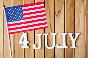 texto del cuatro de julio y bandera de los estados unidos de américa sobre fondo de mesa de madera. EE.UU. fiesta de la independencia y los conceptos de celebración foto