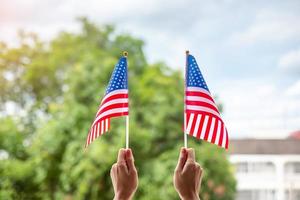 hand holding United States of America flag on blue sky background. USA holiday of Veterans, Memorial, Independence and Labor Day concept photo