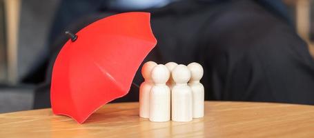 cubierta de paraguas rojo hombre de madera de la multitud de empleados. conceptos de personas, negocios, gestión de recursos humanos, seguros de vida y trabajo en equipo foto