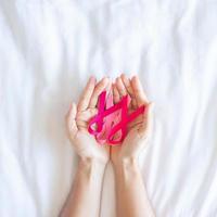 October Breast Cancer Awareness month, adult Woman  hand holding Pink Ribbon on pink background for supporting people living and illness. International Women, Mother and World cancer day concept photo