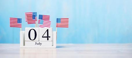Calendario de madera del 4 de julio con bandera en miniatura de los Estados Unidos de América sobre fondo de madera. día de la independencia y concepto de vacaciones nacionales foto