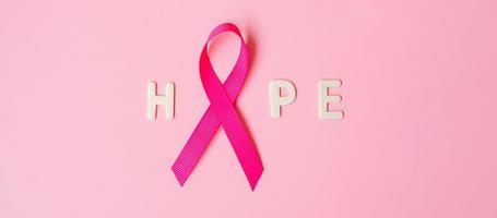 octubre mes de concientización sobre el cáncer de mama, cinta rosa con texto de esperanza sobre fondo rosa para apoyar a las personas que viven y están enfermas. concepto del día internacional de la mujer, la madre y el día mundial del cáncer foto