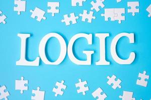 LOGIC text with white puzzle jigsaw pieces on blue background. Concepts of logical thinking, Conundrum, solutions, rational, strategy, world logic day and Education photo