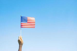 mano que sostiene la bandera de los Estados Unidos de América sobre fondo de cielo azul. fiesta de los veteranos en estados unidos, memorial, independencia y concepto del día del trabajo foto