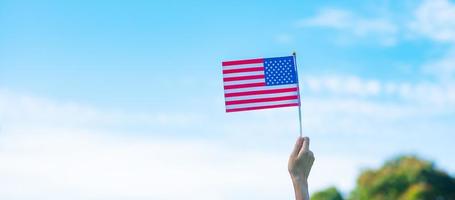 mano que sostiene la bandera de los Estados Unidos de América sobre fondo de cielo azul. fiesta de los veteranos en estados unidos, memorial, independencia y concepto del día del trabajo foto