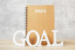 2023 feliz año nuevo con cuaderno y número de madera. concepto de objetivo, cuenta regresiva, resolución, plan, acción y misión foto