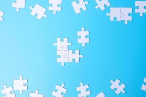Group of white puzzle jigsaw pieces on blue background. Concept of solutions, mission, success, goals, cooperation, partnership, strategy and puzzle day photo