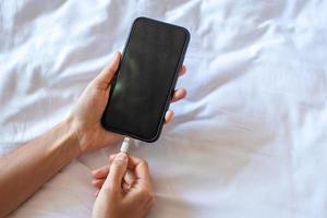 Woman hands charging battery in mobile smart phone in the bedroom at home. Technology, multiple sharing and lifestyle concepts photo