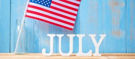 July text and United States of America flag on wooden table background. USA holiday of Independence and celebration concepts photo