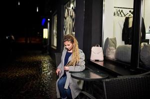 Girl with dreadlocks walking at night street of city. photo