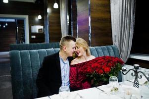 Loving couple in love at restaurant with large bouquet of 101 roses. photo