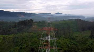 Fly over red and white electric pylon at green rural area video