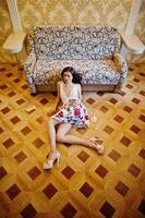 Portrait of an amazing woman in beautiful dress laying on the wooden floor. photo