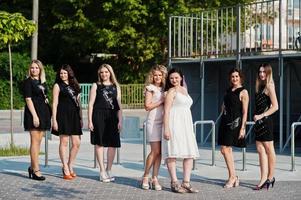 Group of 7 girls wear on black and 2 brides at hen party. photo