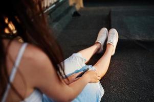 foto de primer plano de la mano de una mujer sosteniendo un teléfono con auriculares conectados.