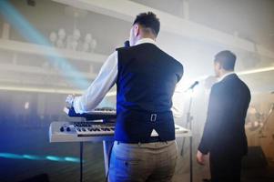 Musicial music live band performing on a stage with different lights. Keyboardist play. photo