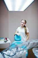 una dentista guapa posando con bata blanca en un gabinete moderno y bien equipado. foto