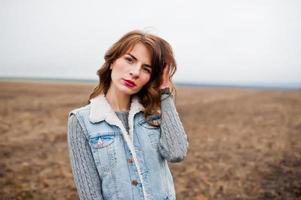 Portrait of brunette curly girl in jeans jacket at field. photo