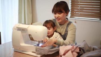 padres e hijos usando una máquina de coser video