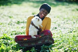 African american girl at yellow and red dress with white rabbit at hands. photo