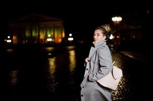 Girl with dreadlocks walking at night street of city. photo