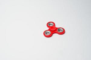 Close-up photo of a red fidget spinner on a white background.