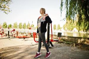 la joven tiene el entrenamiento y hace ejercicio al aire libre en simuladores callejeros. deporte, fitness, concepto de entrenamiento callejero. foto