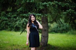 retrato de una hermosa chica vestida de negro en una despedida de soltera, posada en el parque. foto