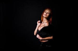 Fashion model red haired girl with originally make up like leopard predator isolated on black. Studio portrait. photo