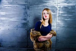 Elegante blonde girl wear on fur coat and combi dress against steel wall on studio. photo