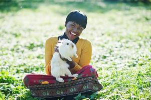 African american girl at yellow and red dress with white rabbit at hands. photo