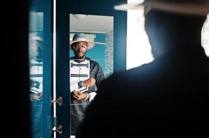 Rich african man looking at mirror on wardrobe at his appartment. Portrait of successful black man indoor. photo